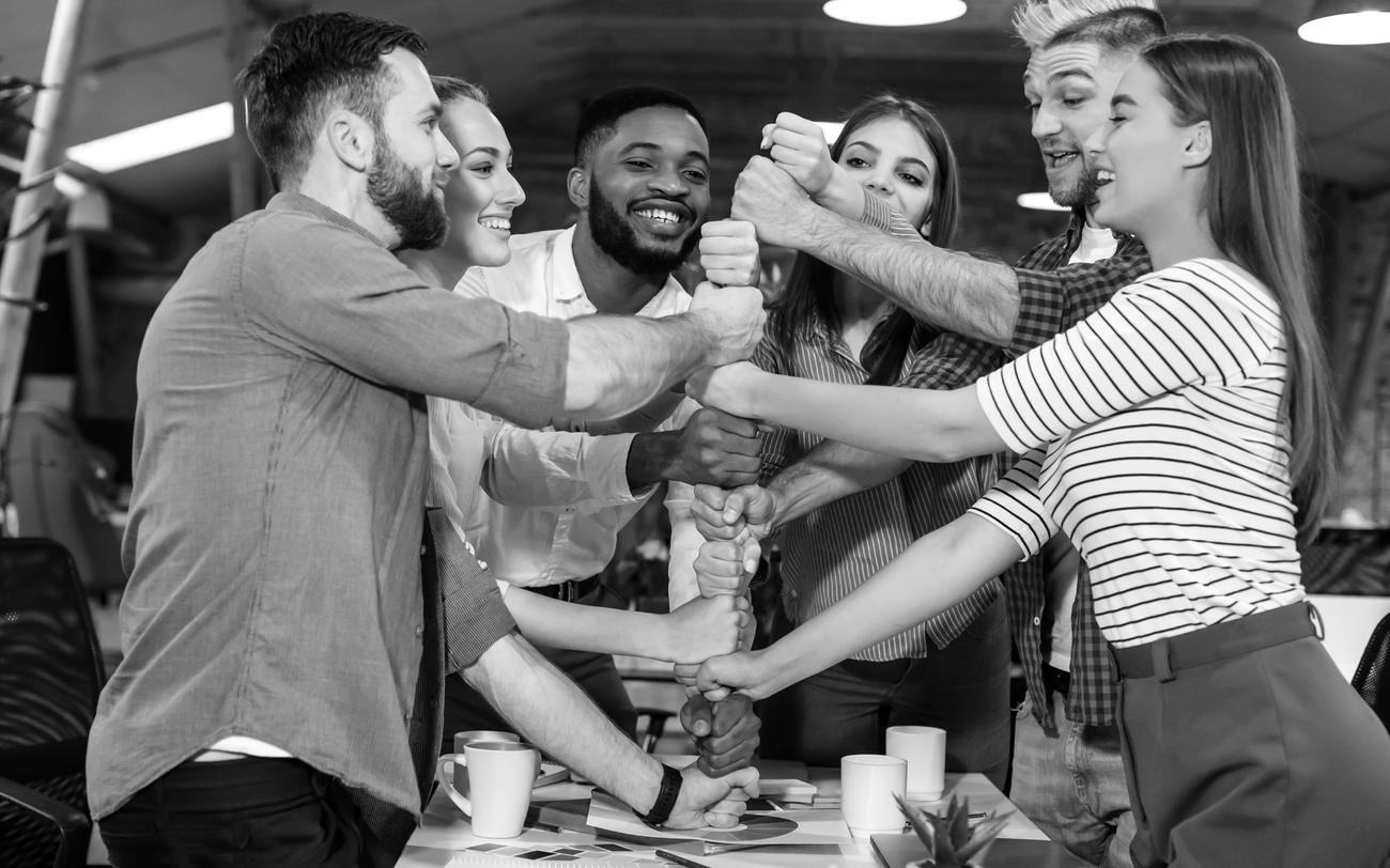 Équipe en team building poings serrés au bureau, en noir et blanc - So Events 31
